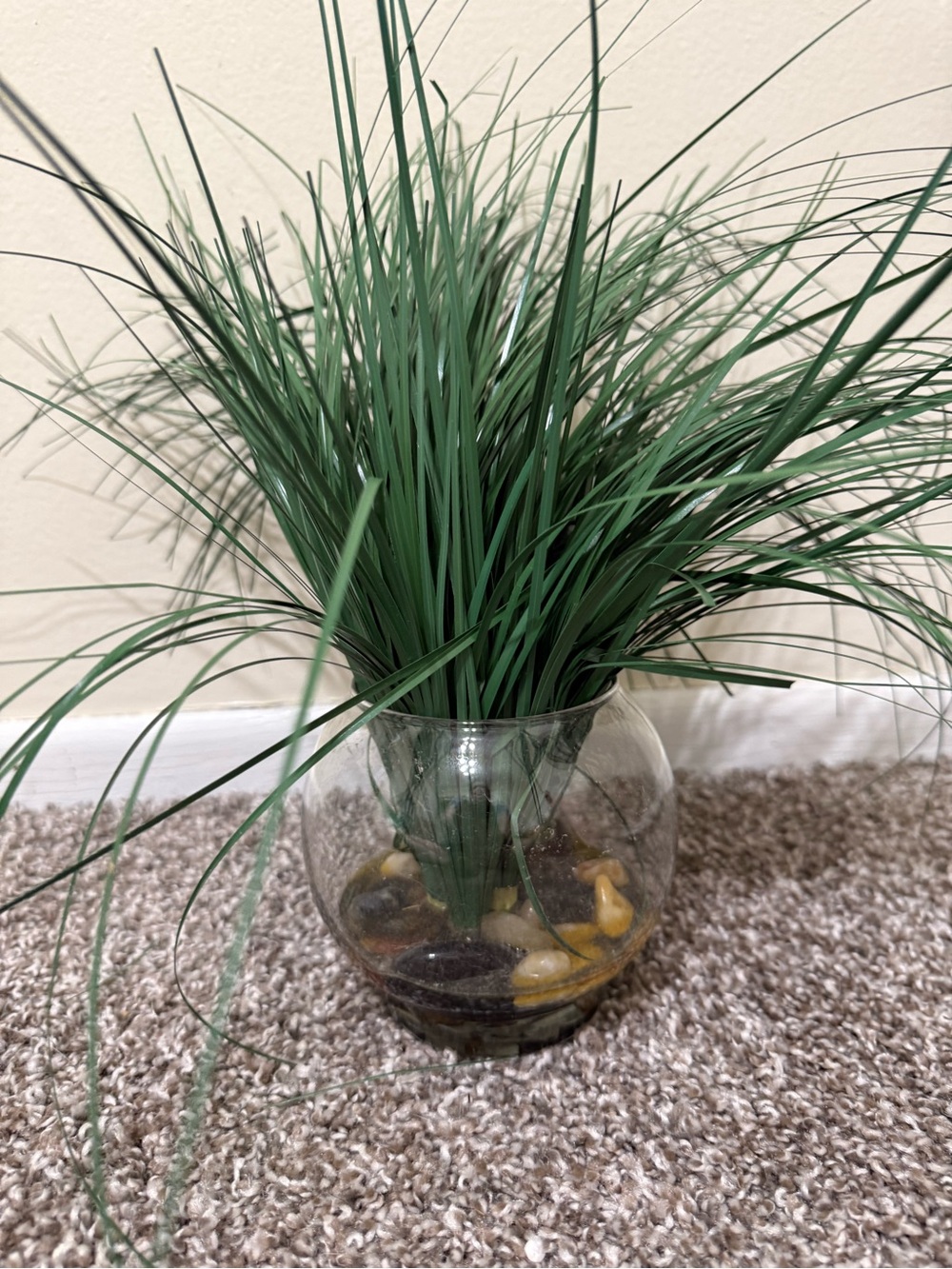 Artificial plant in glass round vase with rocks